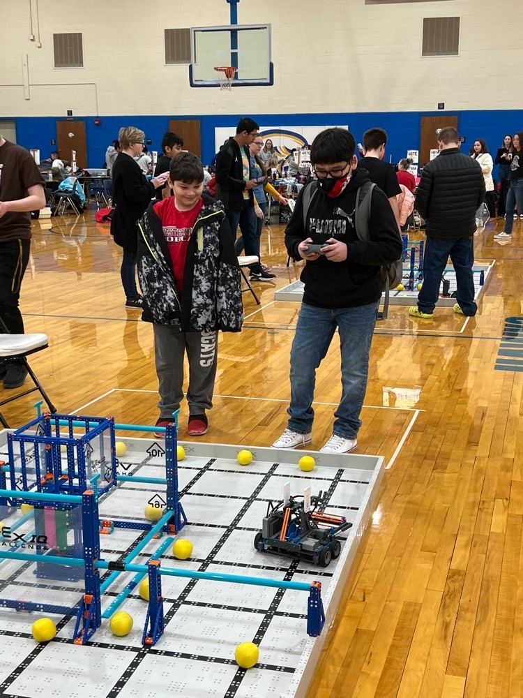 students are driving their robot to score during a team work challenge.