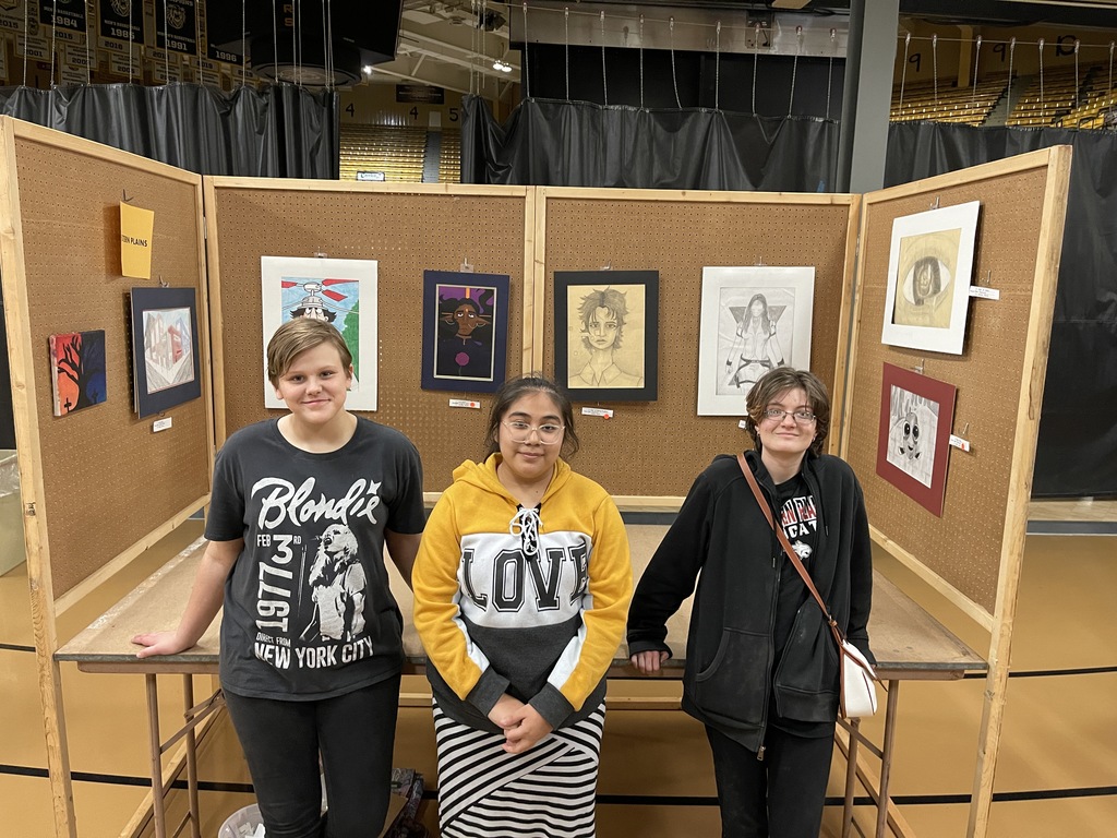 Students pose in front of their hung artwork for the juried exhibition.